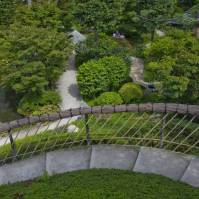 Serpentína štrkového schodišťa s prírodným zábradlím nás vedie až k vodnej ploche v zajatí bohatej zelene (japonská záhrada, Francúzsko)