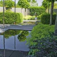 Postmoderná záhrada s vodným chrličom a vodnými plochami integrujúca vonkajší obytný priestor (Holandsko)